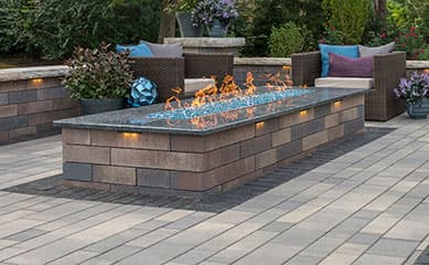 Linear gas fire feature with blue glass on a paver patio
